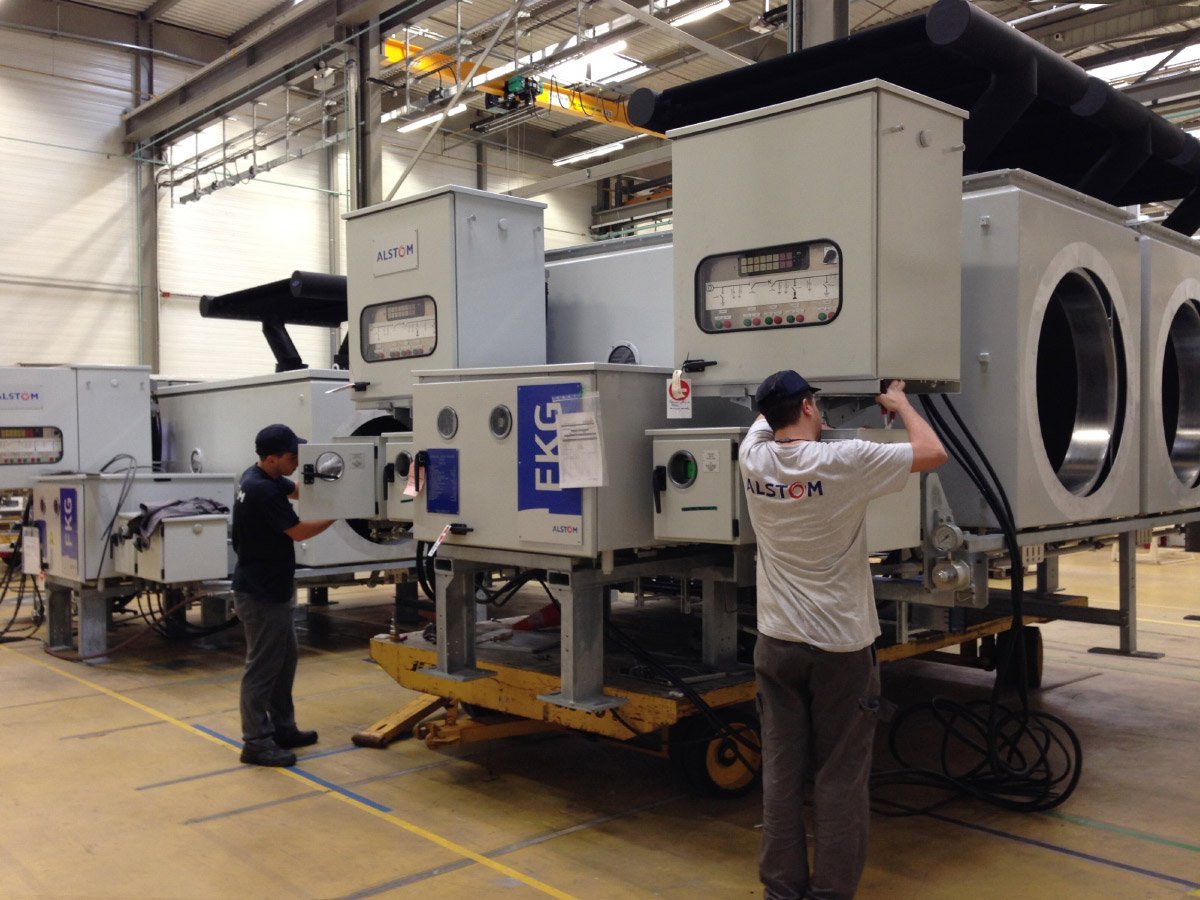 Men working on a machine in a factory
Description automatically generated