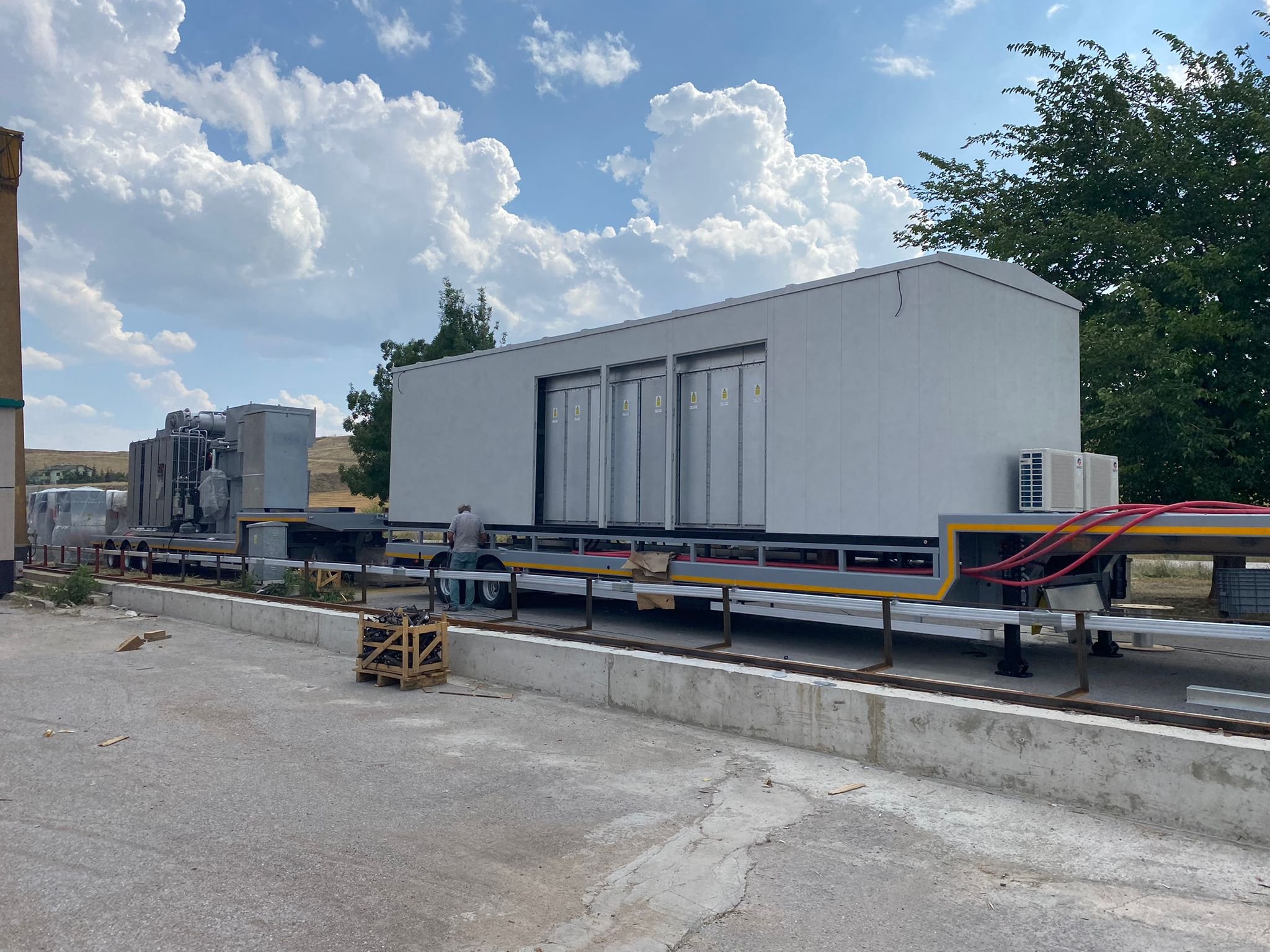A white trailer with a blue sky and clouds
Description automatically generated