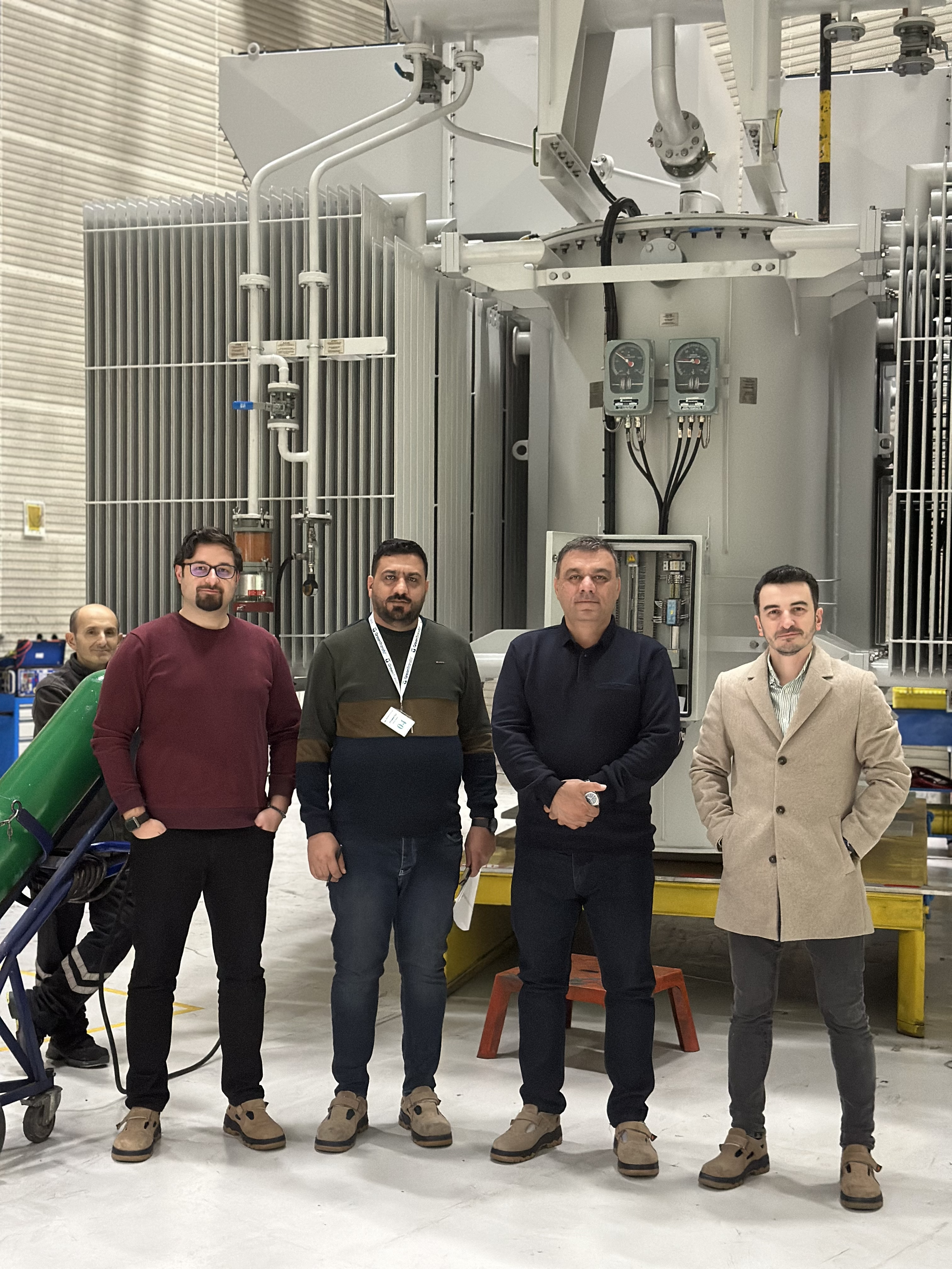 A group of men standing in front of a machine
Description automatically generated